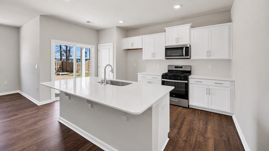 Modern kitchen space in new home for sale with white cabinets, white quartz countertops, and stainless-steel appliances