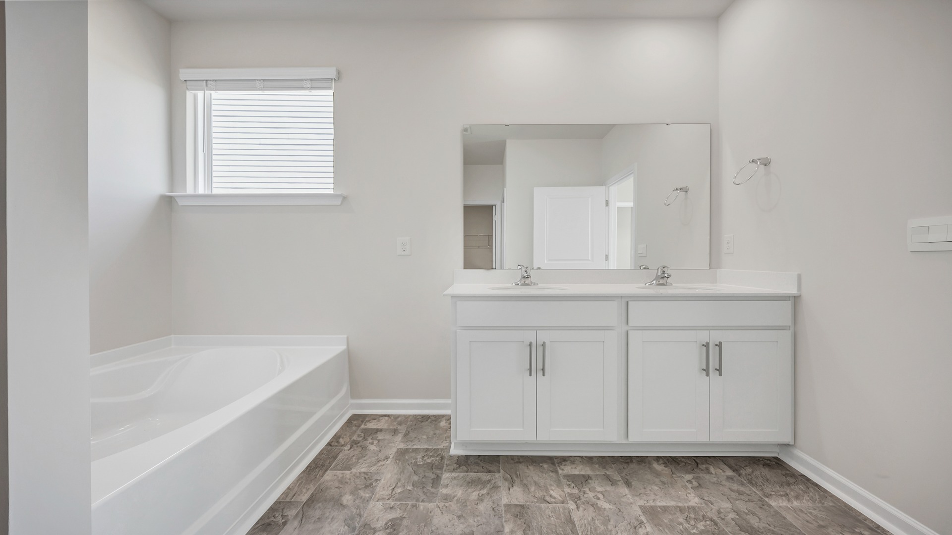 Garden tub in the Cali primary bathroom with a high window for natural light in the bathroom