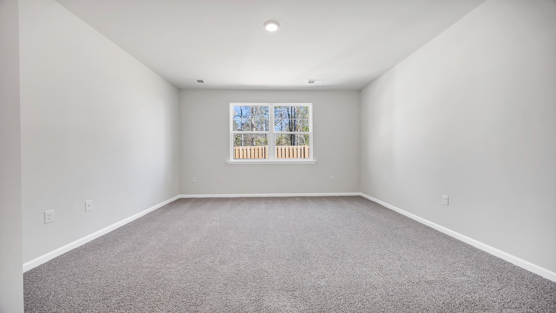 Primary bedroom downstairs with carpet floors and a window facing the large back yard in Sumter, SC