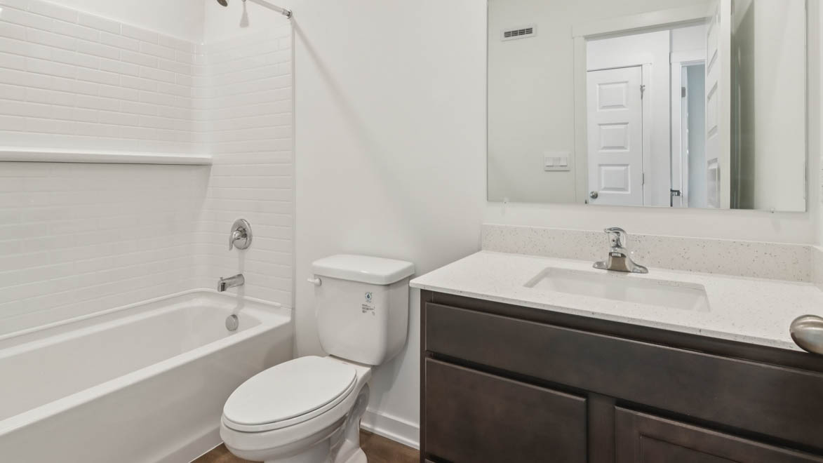 Family bathroom with stylish vanity, mirror, polished fixtures, cabinets, tub-shower combo in Station Heights