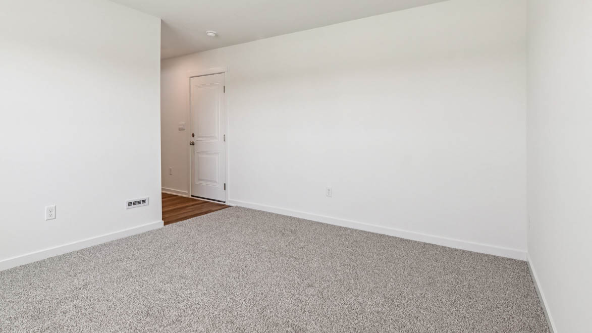 Multi-use basement room with neutral tones and doorways leading townhome and garage