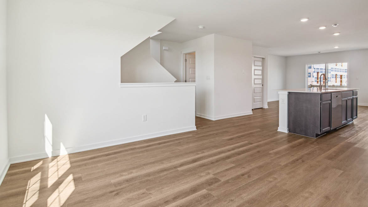 Dining room looking toward modern kitchen island with sink and new appliance suite included, next to upstairs access