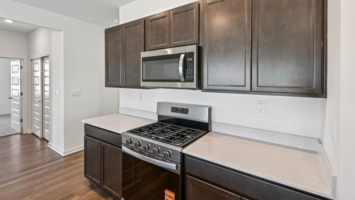 Kitchen with upper and lower dark cabinets and white quartz countertops