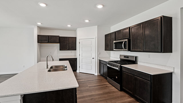 Interior kitchen with center island and dark cabinets