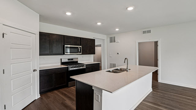 Interior kitchen with center island and dark cabinets