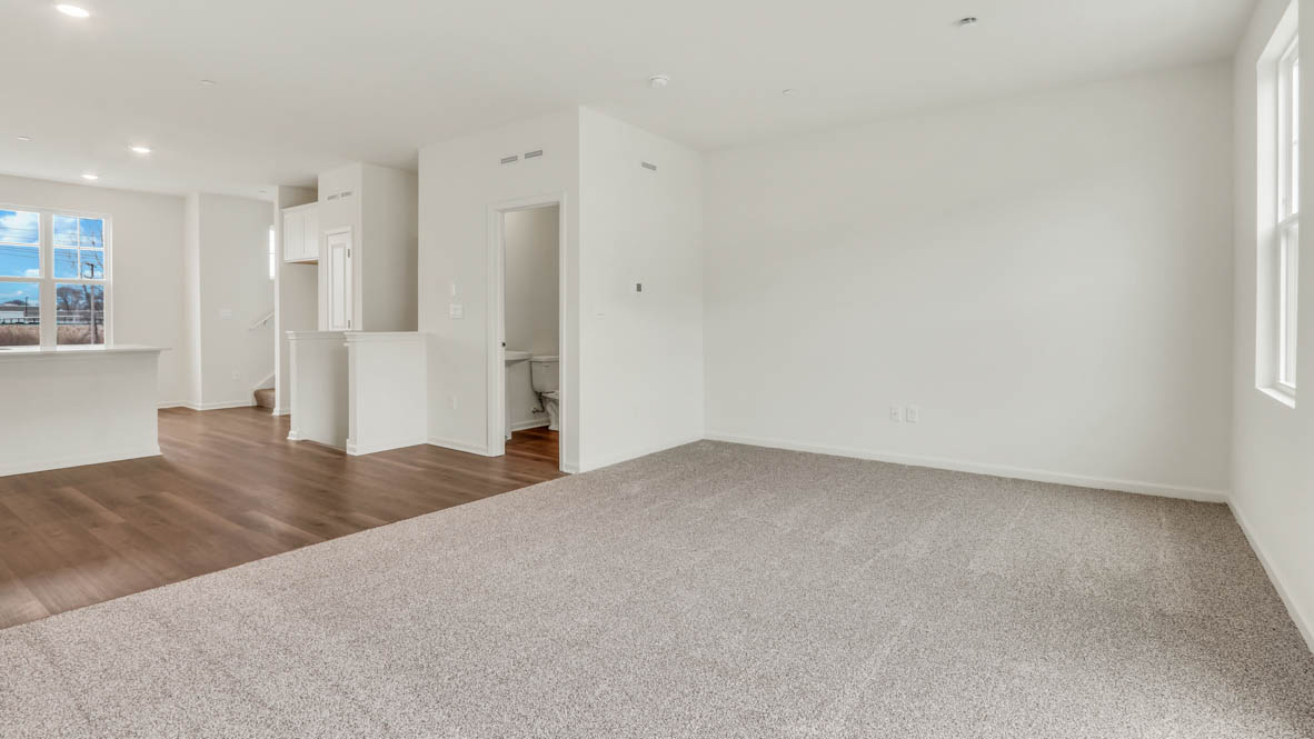 Living room looking to dining and kitchen areas in this new home features natural light, with fresh open concept flow