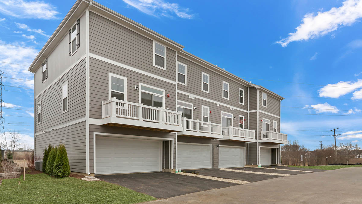 Exterior of back of townhome with attached 2 car garages and large balcony