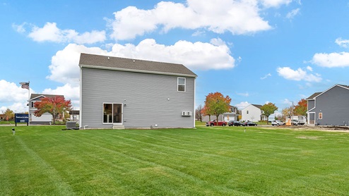 backside of the home with lush grass in the backyard