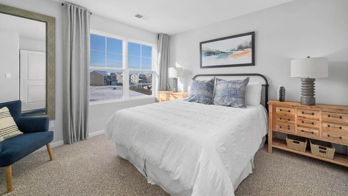 Bedroom with a large window and carpeted floors.