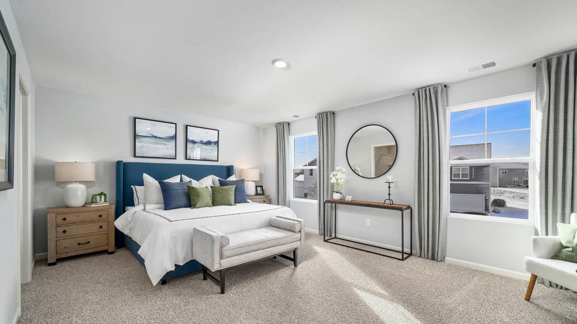 Primary bedroom with large windows for natural lighitng and carpeted floors.