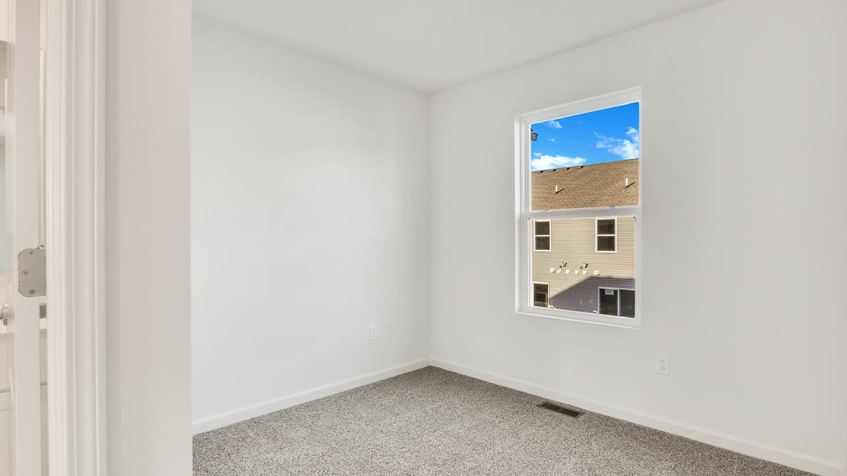 bedroom with beige carpet, white walls and a window