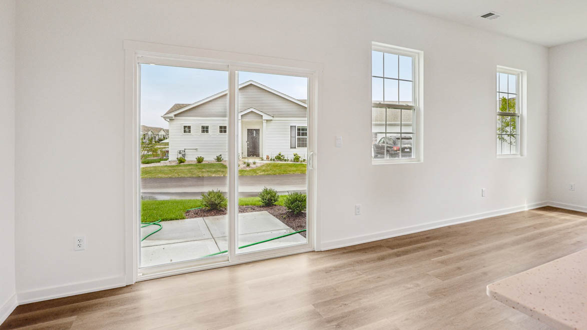 Dining room looking toward modern kitchen island with sink and new appliance suite included, next to backyard at Stonewater