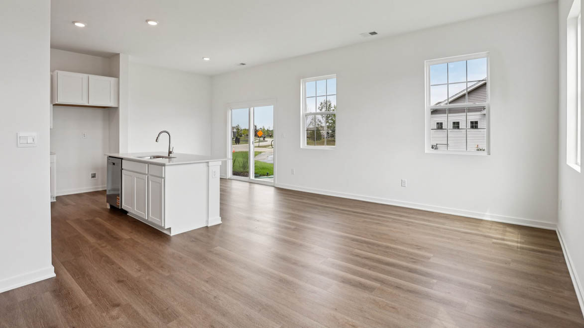 Spacious living room with view into dining and kitchen areas, and outside access at Stonewater