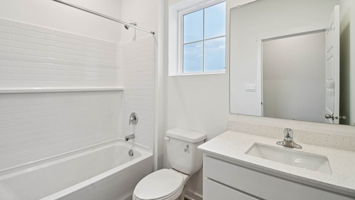 Sleek family-guest bath with single sink, mirror, cabinets, and shower-tub combination at Stonewater