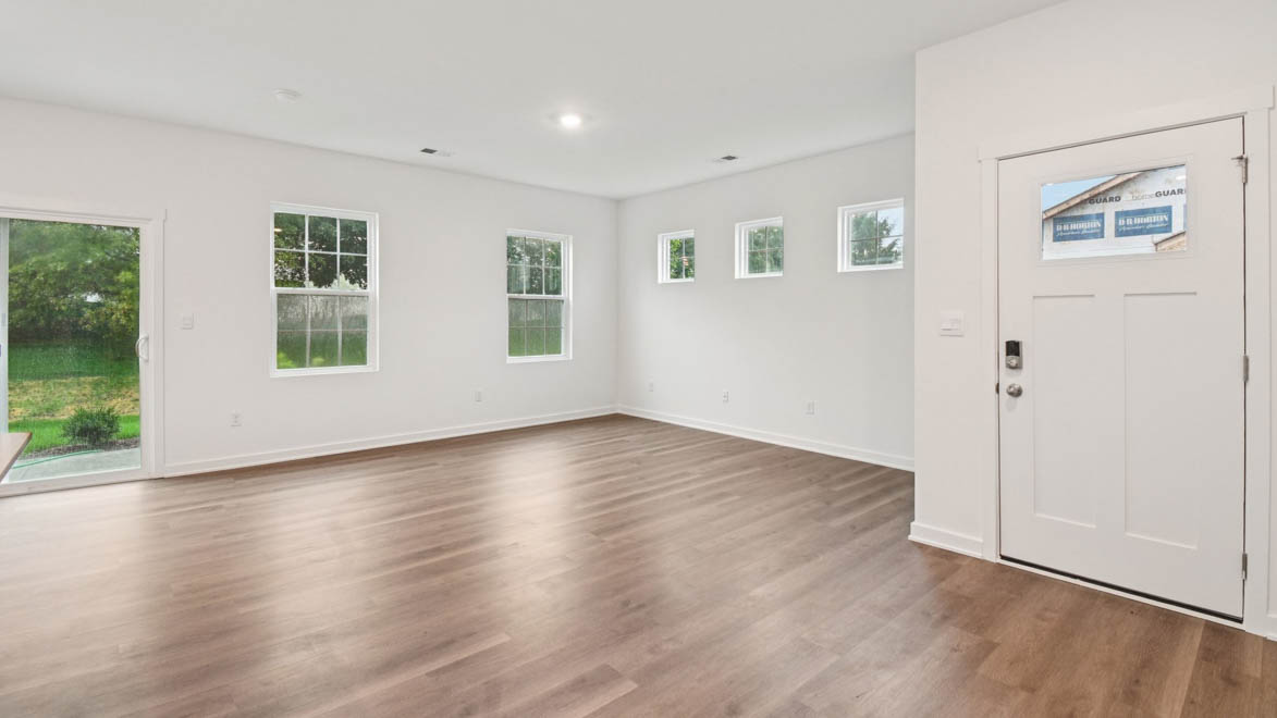 Spacious living room with large windows, natural light, near dining, kitchen areas in this new build home