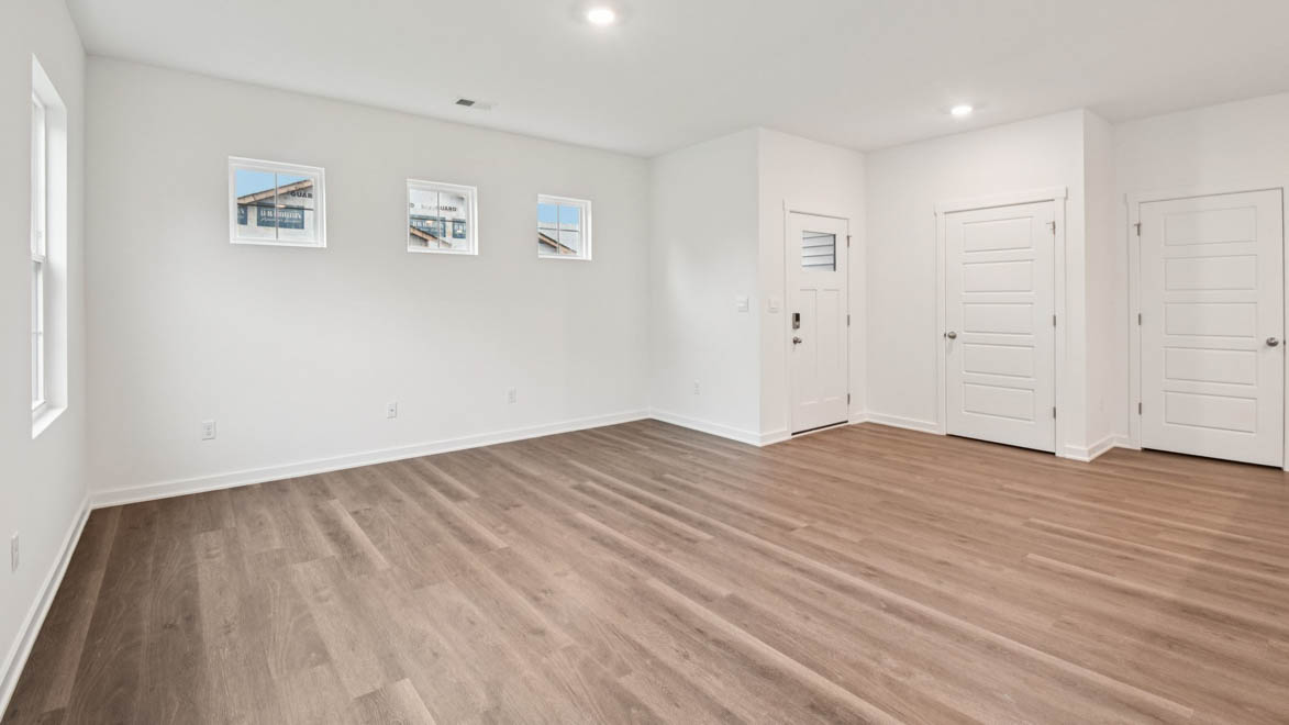Living room in this new construction home features natural light, with fresh open concept flow to the kitchen, dining areas