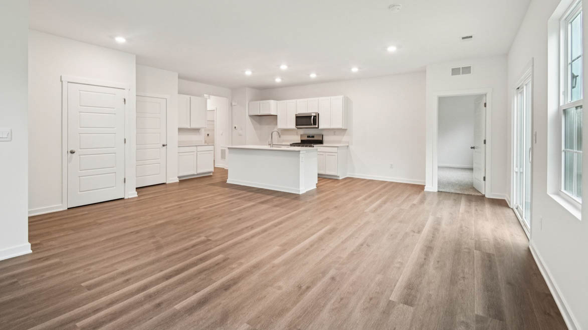 Spacious living room with view into dining and kitchen areas, and outside access at Stonewater