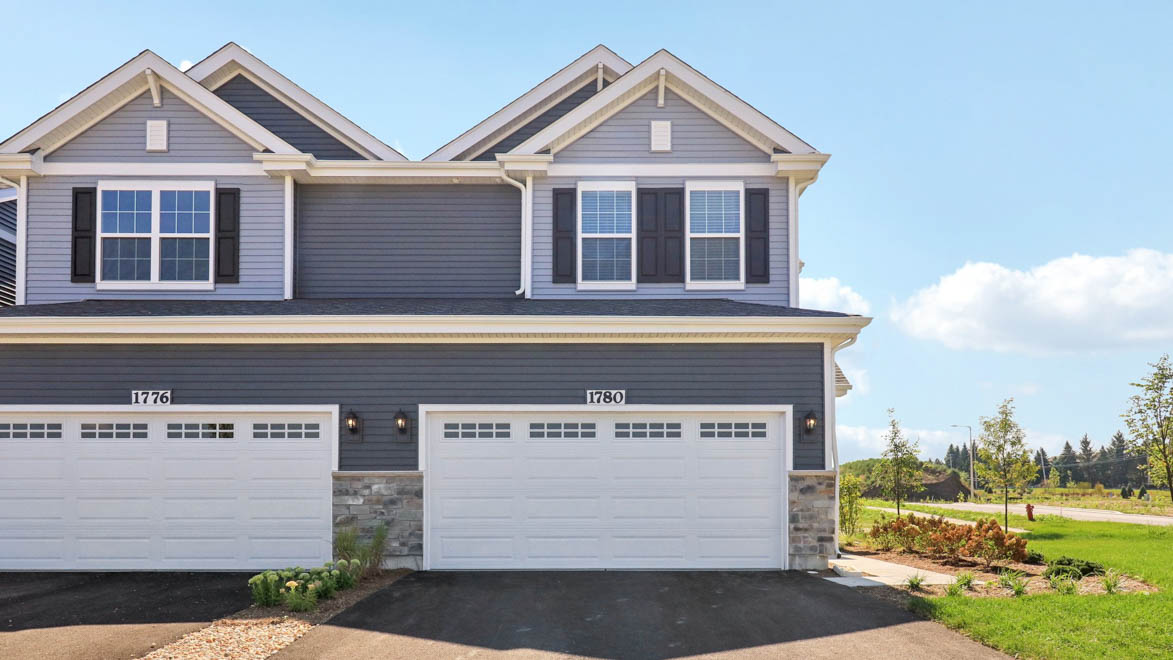 front exterior of a townhome with grey siding and a 2 car gargae