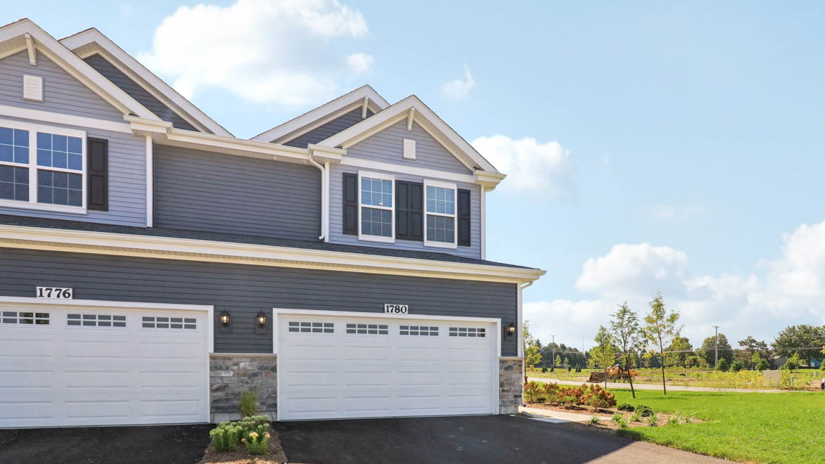 front exterior of a townhome with grey siding and a 2 car gargae