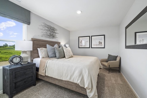 Spacious guest room with a bed and chair in Ivanhoe Holcombe model