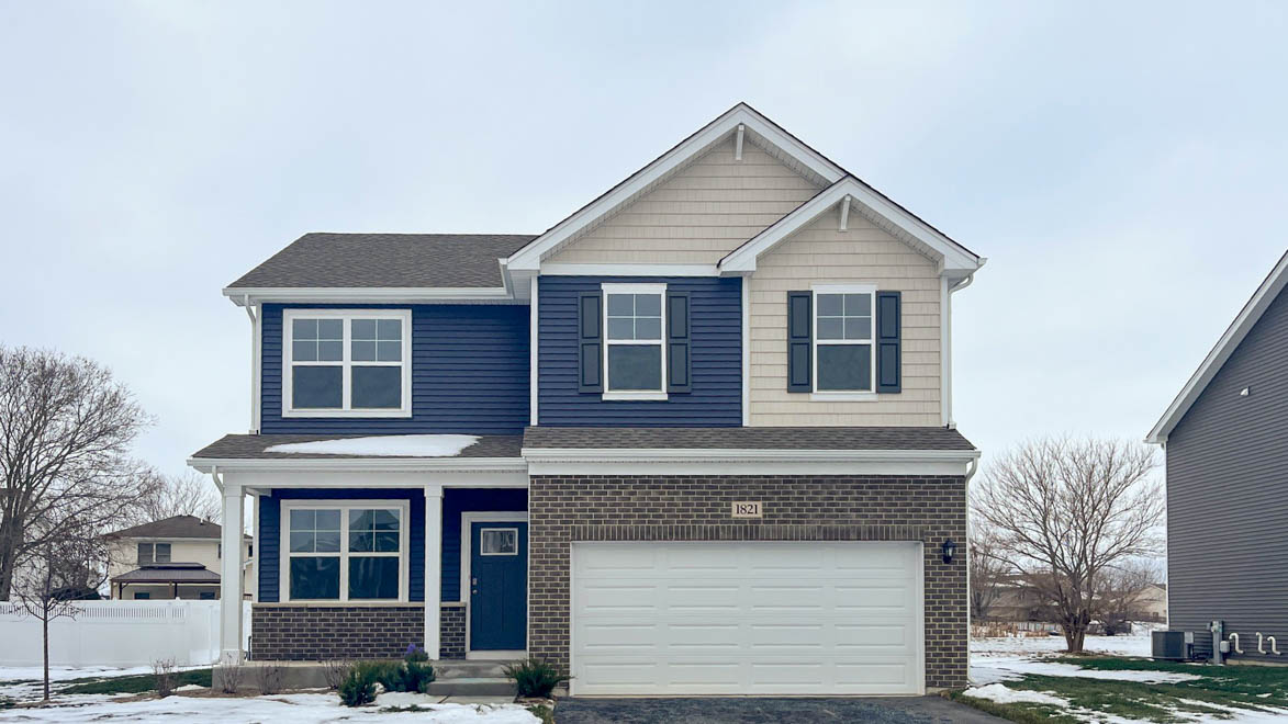 Two story home with vinyl siding and brick exterior and a front porch