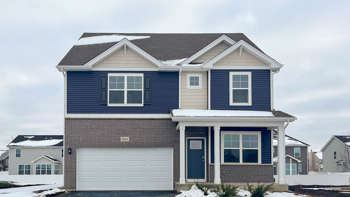 Holcombe exterior with blue vinyl siding, brick, and a front porch