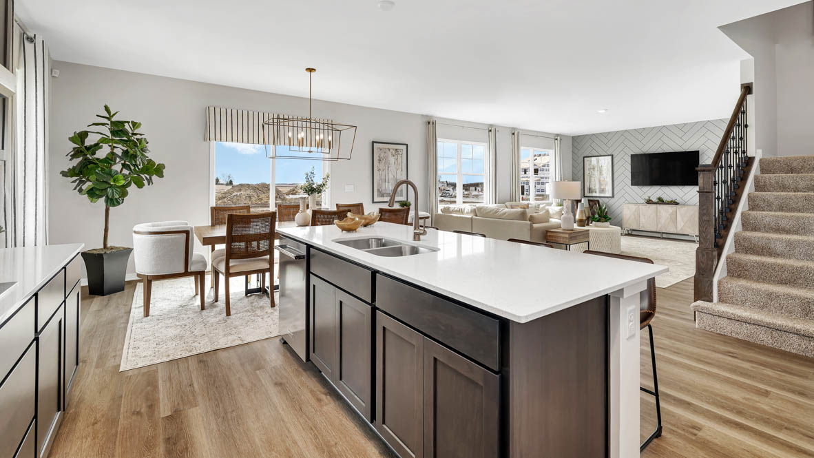 Kitchen island with a sink and dishwasher overlooking great room