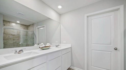 Primary bathroom with dual sinks and walk in closet