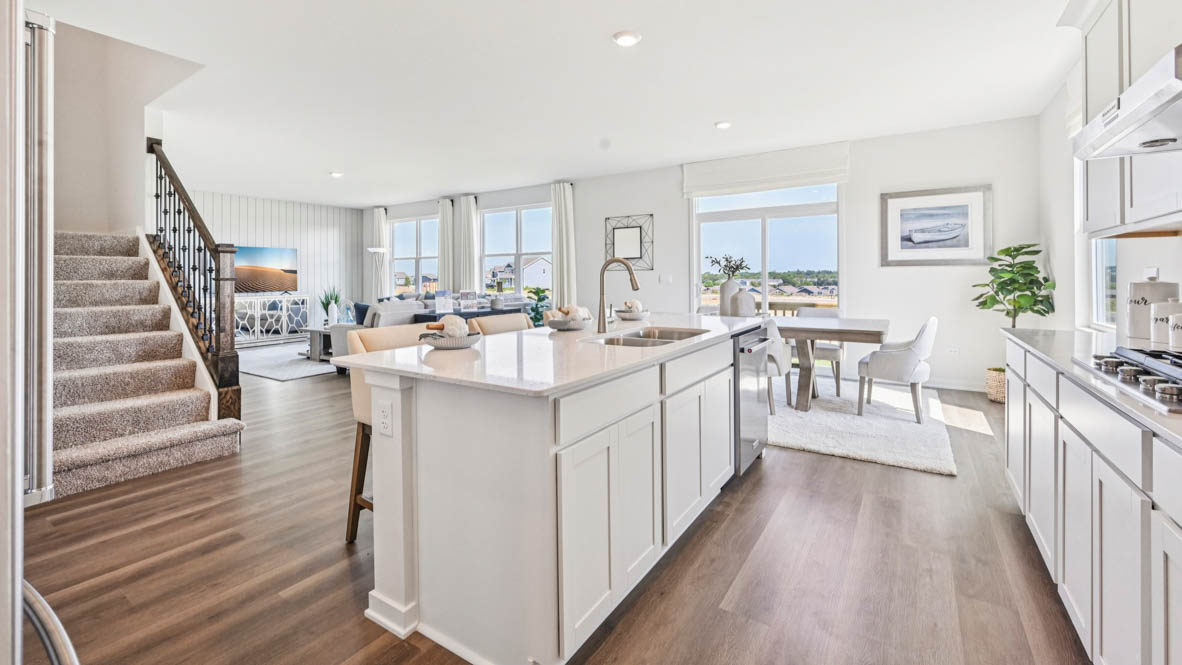 Kitchen island with a sink and dishwasher overlooking great room