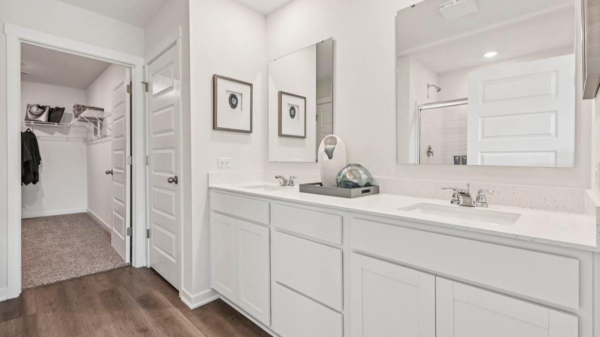 Primary bathroom with dual sinks and walk in closet
