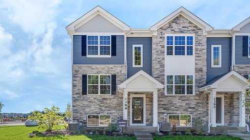 3-story townhome building with blue vinyl siding and stone accents