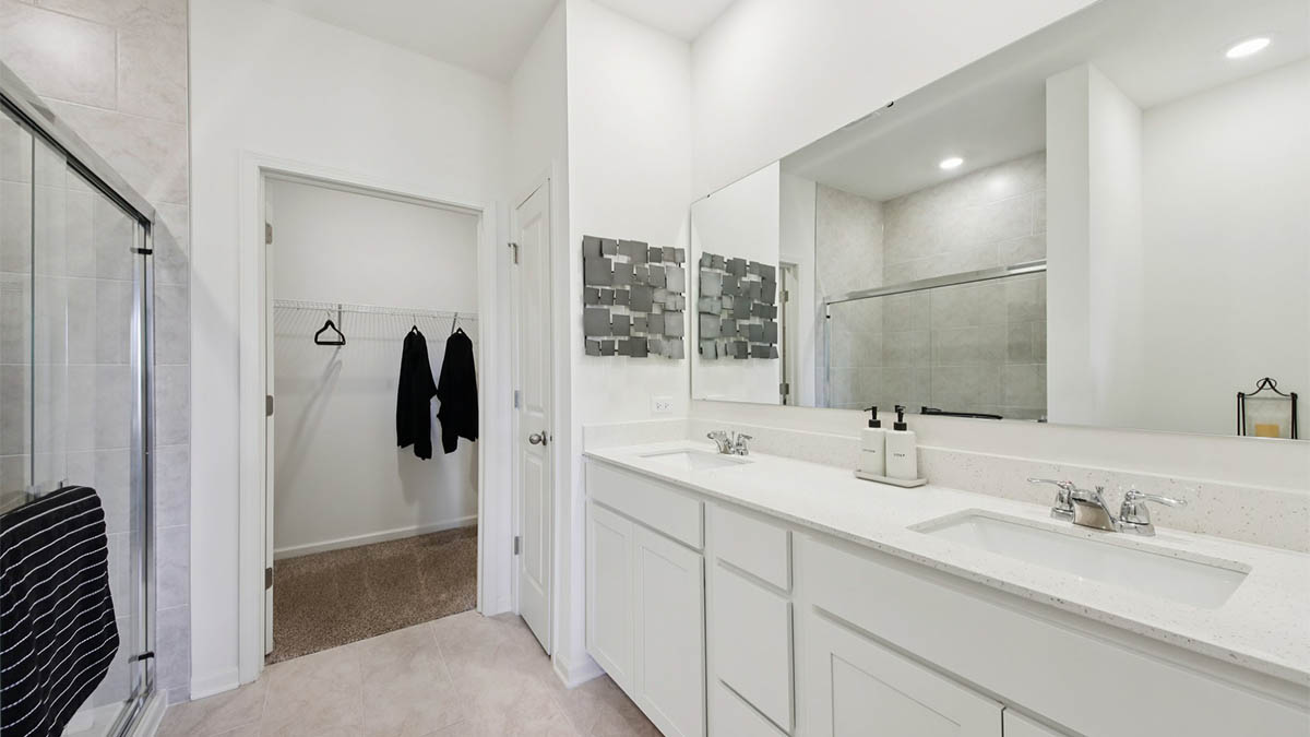 primary en suite bathroom with double bowl vanity and walk-in closet