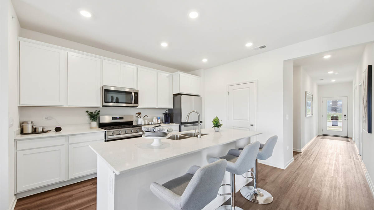 open concept kitchen with stainless steel appliances and white cabinetry