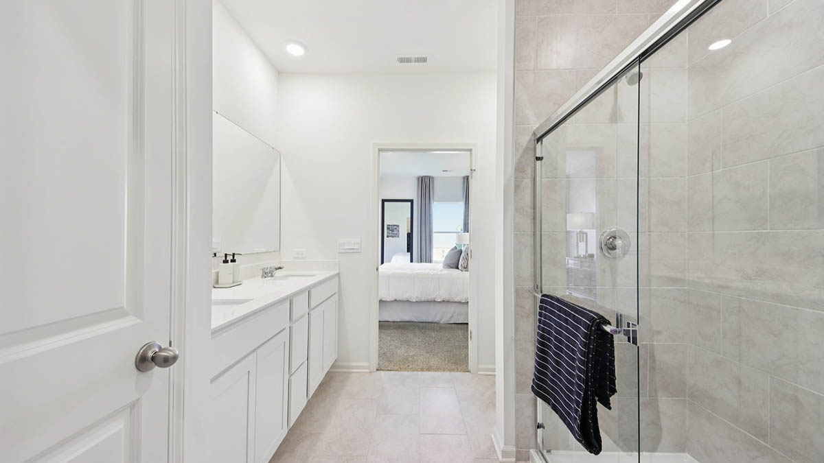 primary en suite bathroom with double bowl vanity and walk in shower