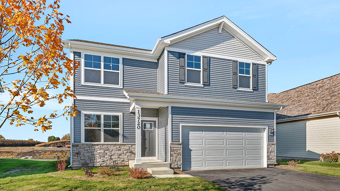 front of home with fully sodded yard and tree
