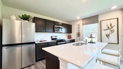 Open concept kitchen with dark cabinets, stainless steel appliances, and kitchen island
