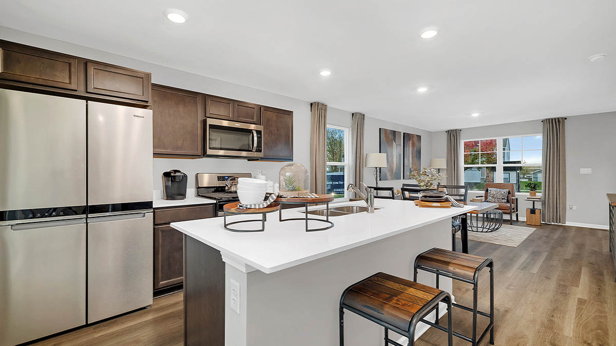 open concept kitchen with dark brown cabinets and quartz countertops