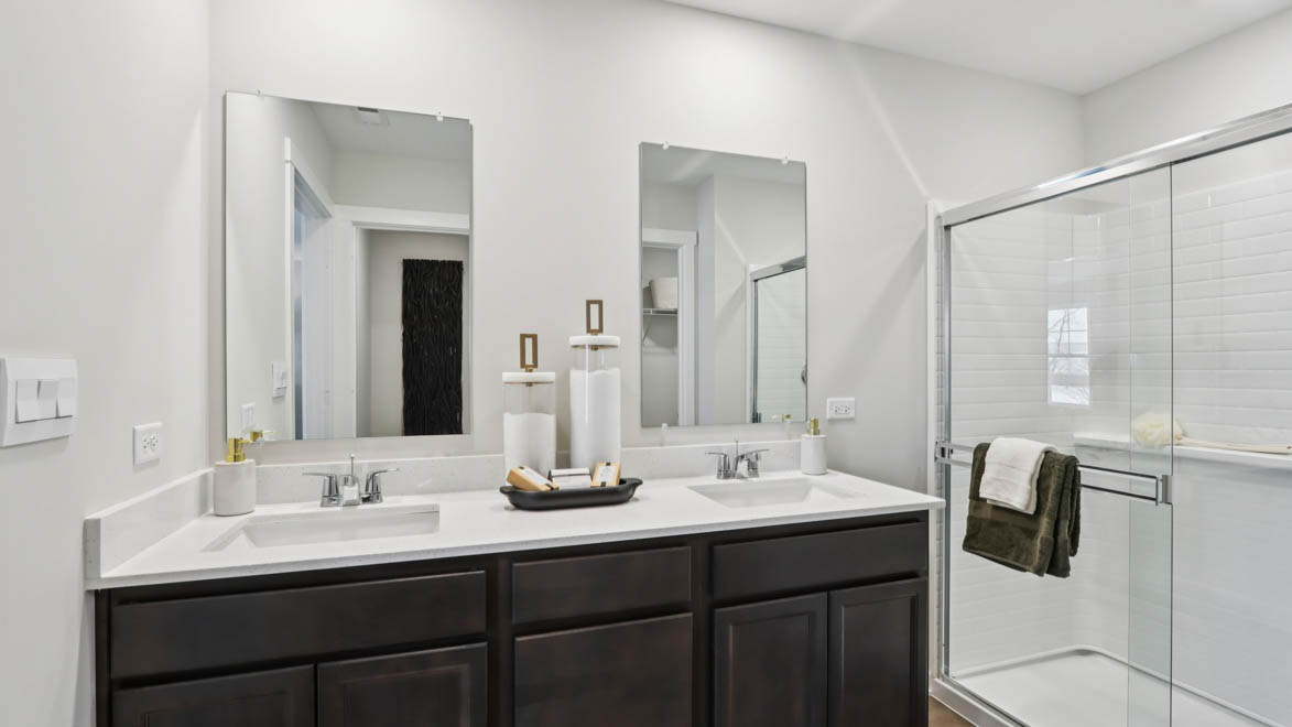 bathroom with dual sinks and walk in shower