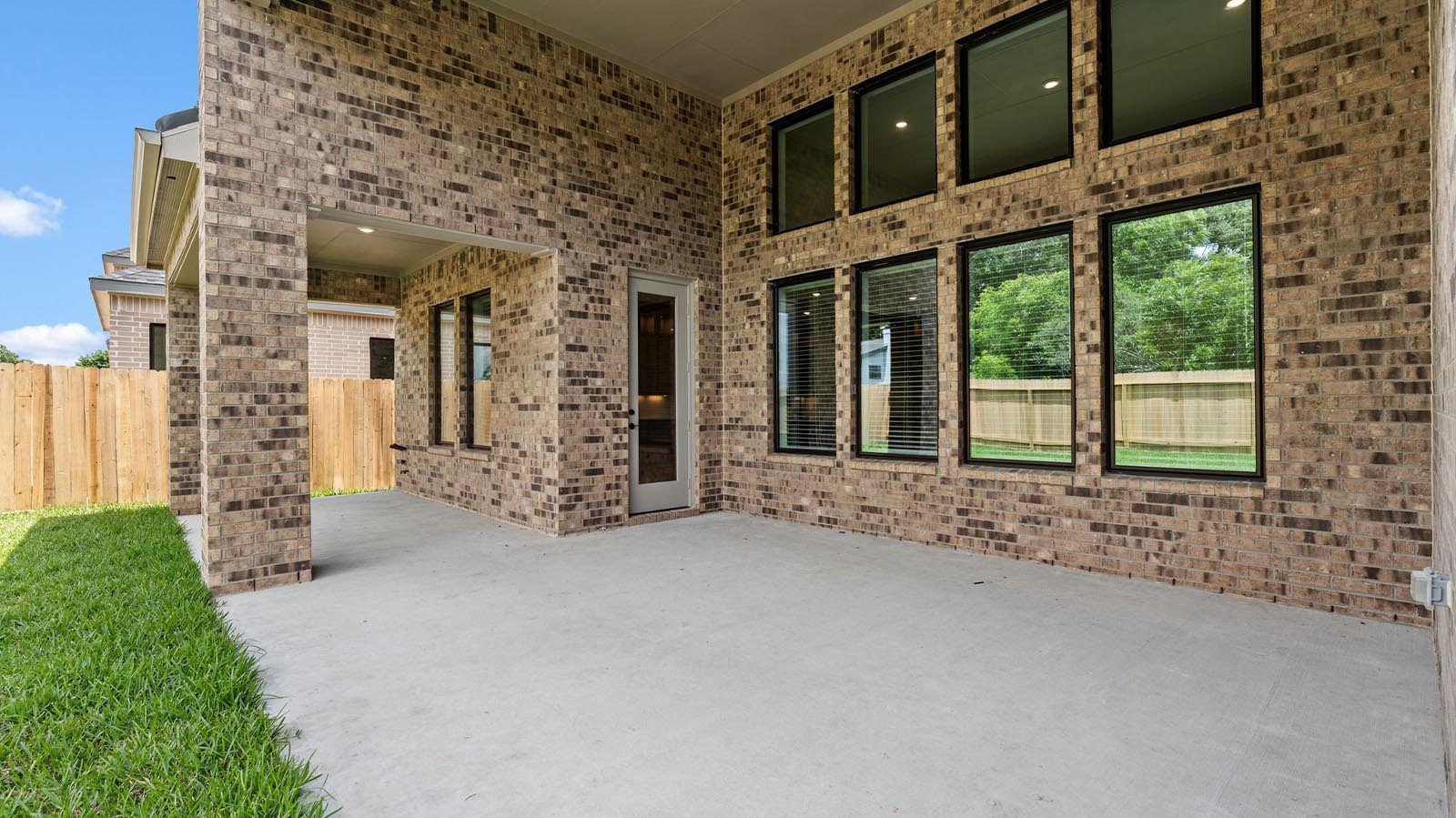 Outdoor covered patio with seating area overlooking a well-maintained lawn, perfect for relaxation.