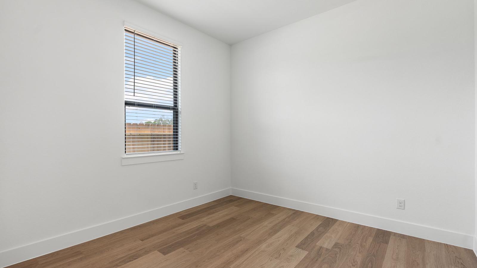 A fourth bedroom with one window, space that fits a queen size bed and additional bedroom furniture