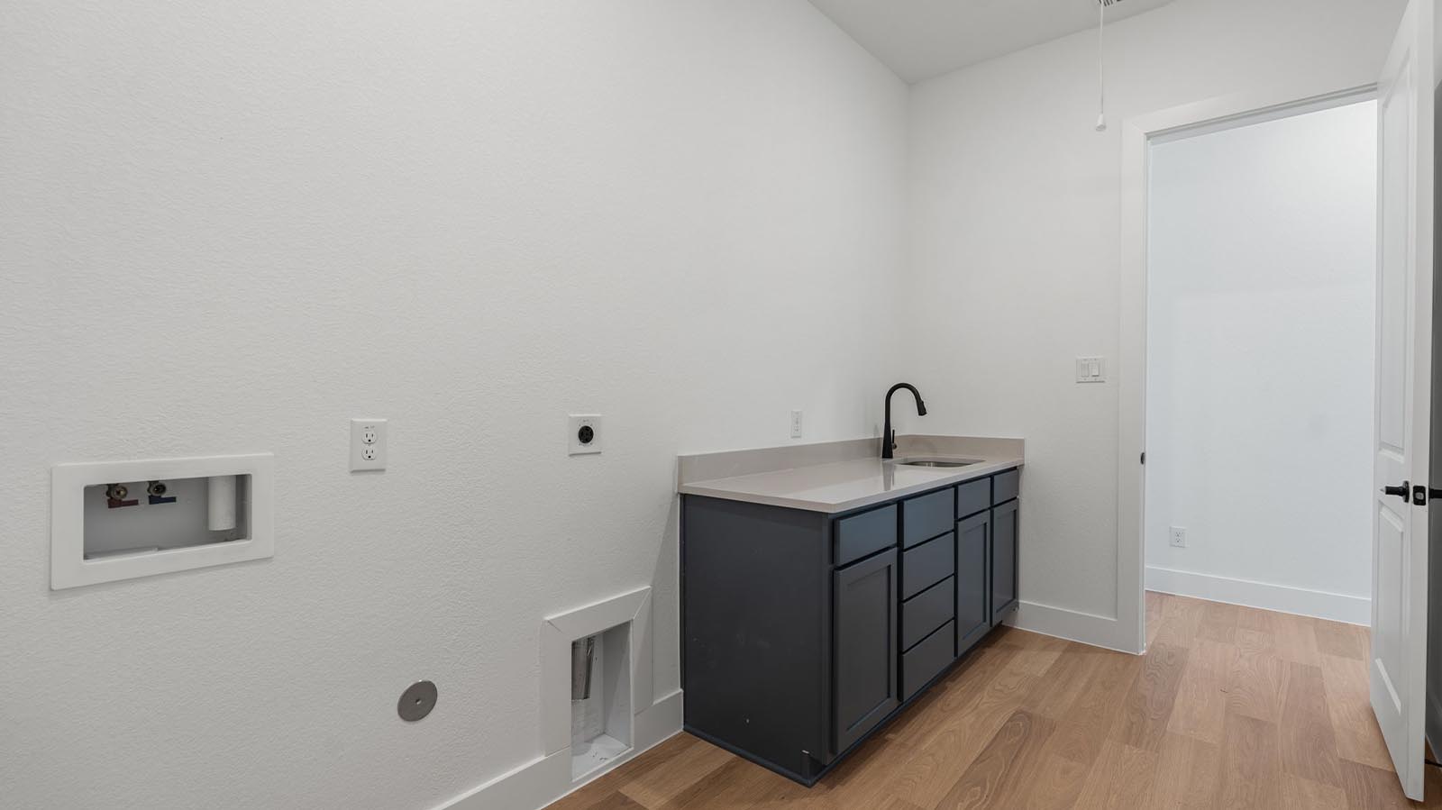 A laundry room featuring washer and dryer connections, neatly arranged with ample space for laundry tasks, and storage.