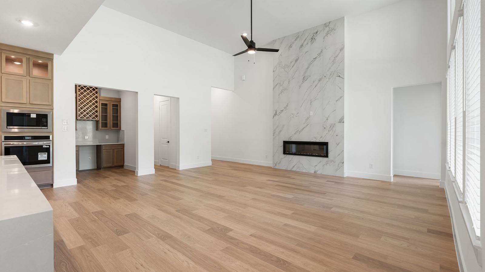 Elegant living room with soaring ceilings, a cozy electric fireplace, open-concept design, and seamless flow into a chef-inspired kitchen.
