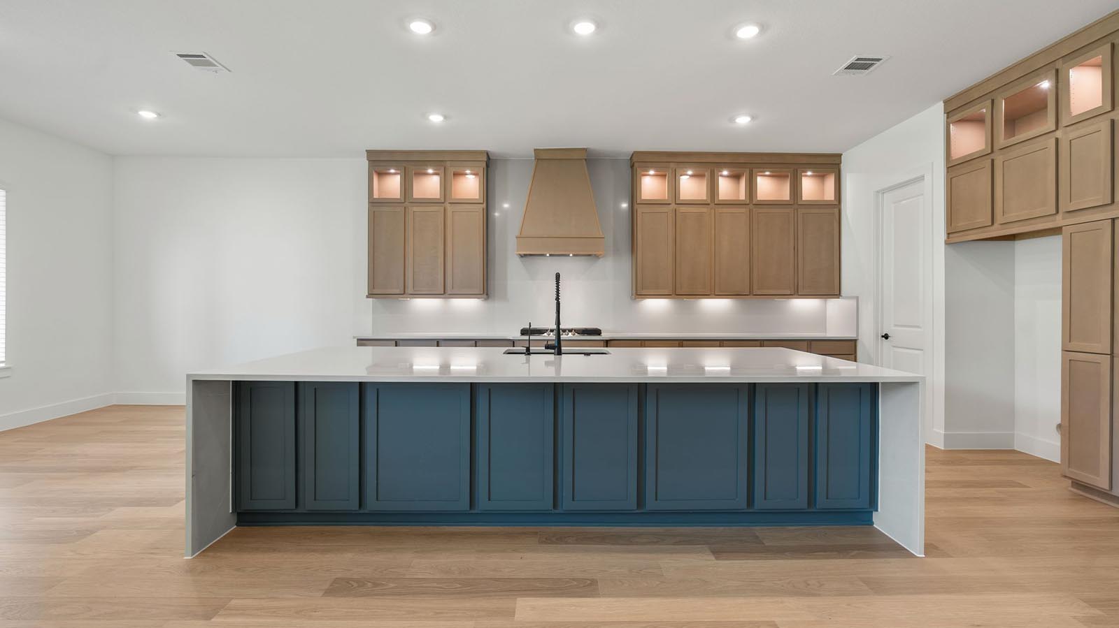 Luxurious and spacious kitchen with quartz countertops, stainless steel appliances,  stained wood cabinets, expansive storage and an island with bar seating.