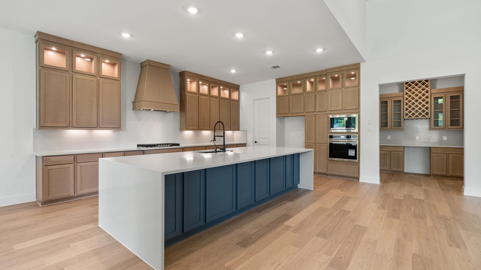 Luxurious and spacious kitchen with quartz countertops, stainless steel appliances, wood cabinets with natural stain, expansive storage and an island with bar seating.