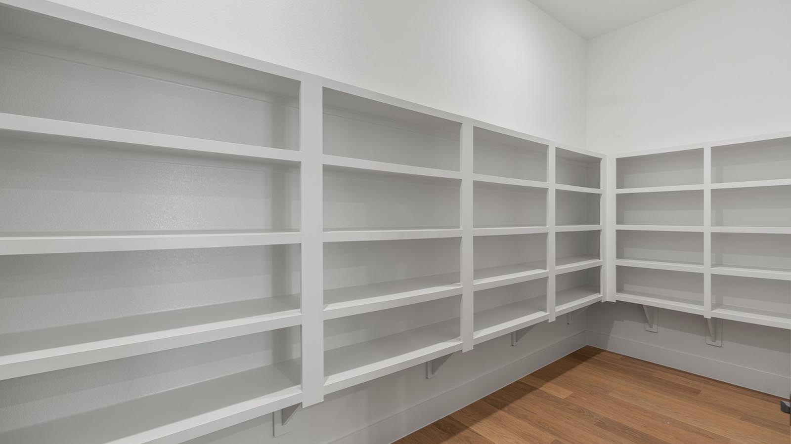 A spacious walk-in kitchen pantry with built in shelves for additional storage