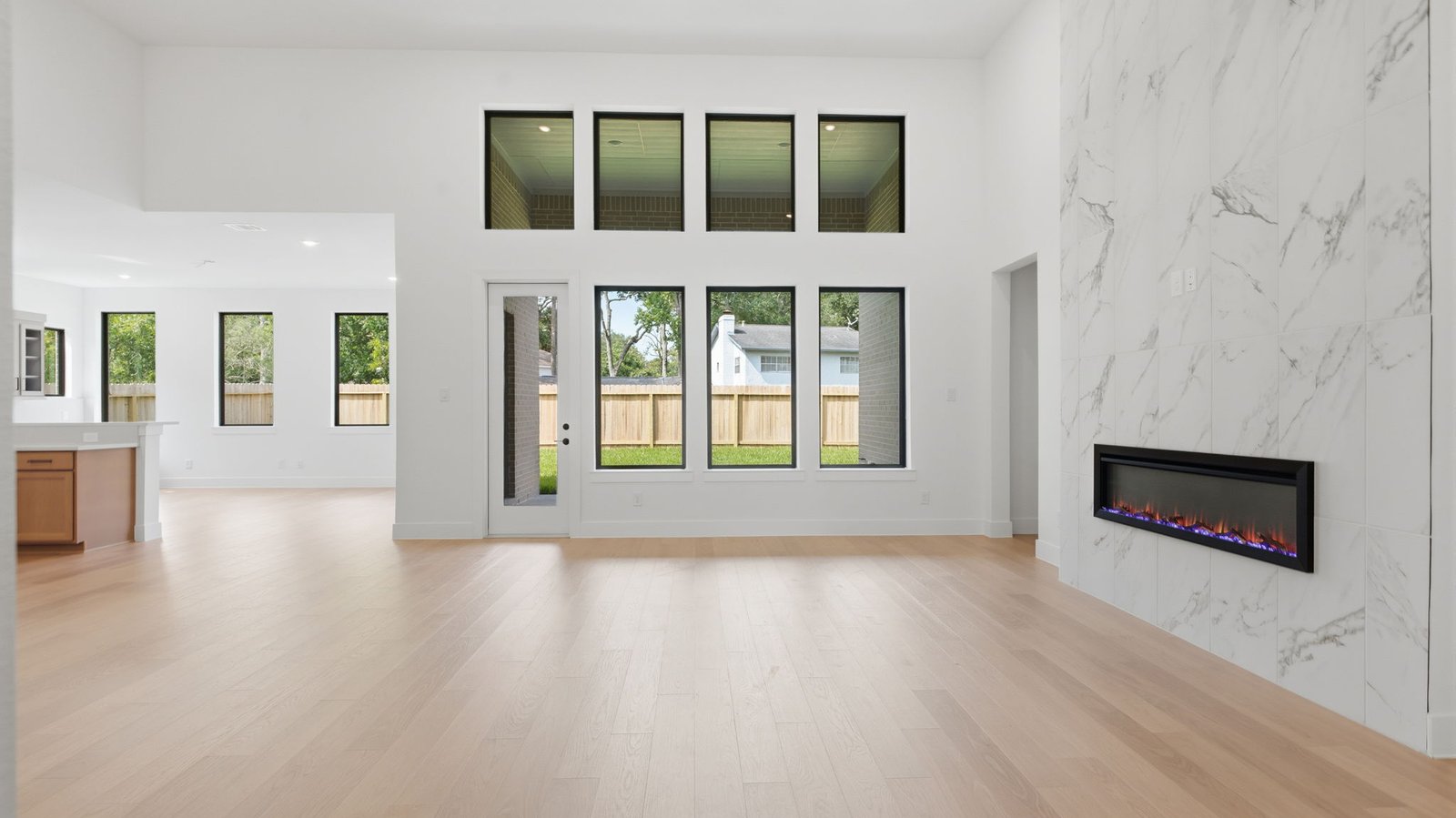 Elegant living room with soaring ceilings, a cozy electric fireplace, open-concept design, and seamless flow into a chef-inspired kitchen.