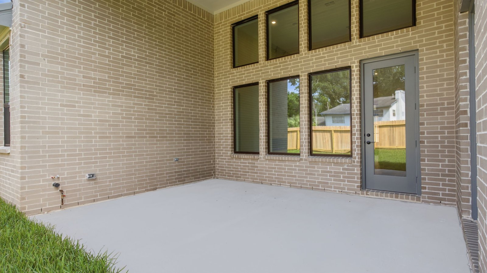 Outdoor covered patio with seating area overlooking a well-maintained lawn, perfect for relaxation.