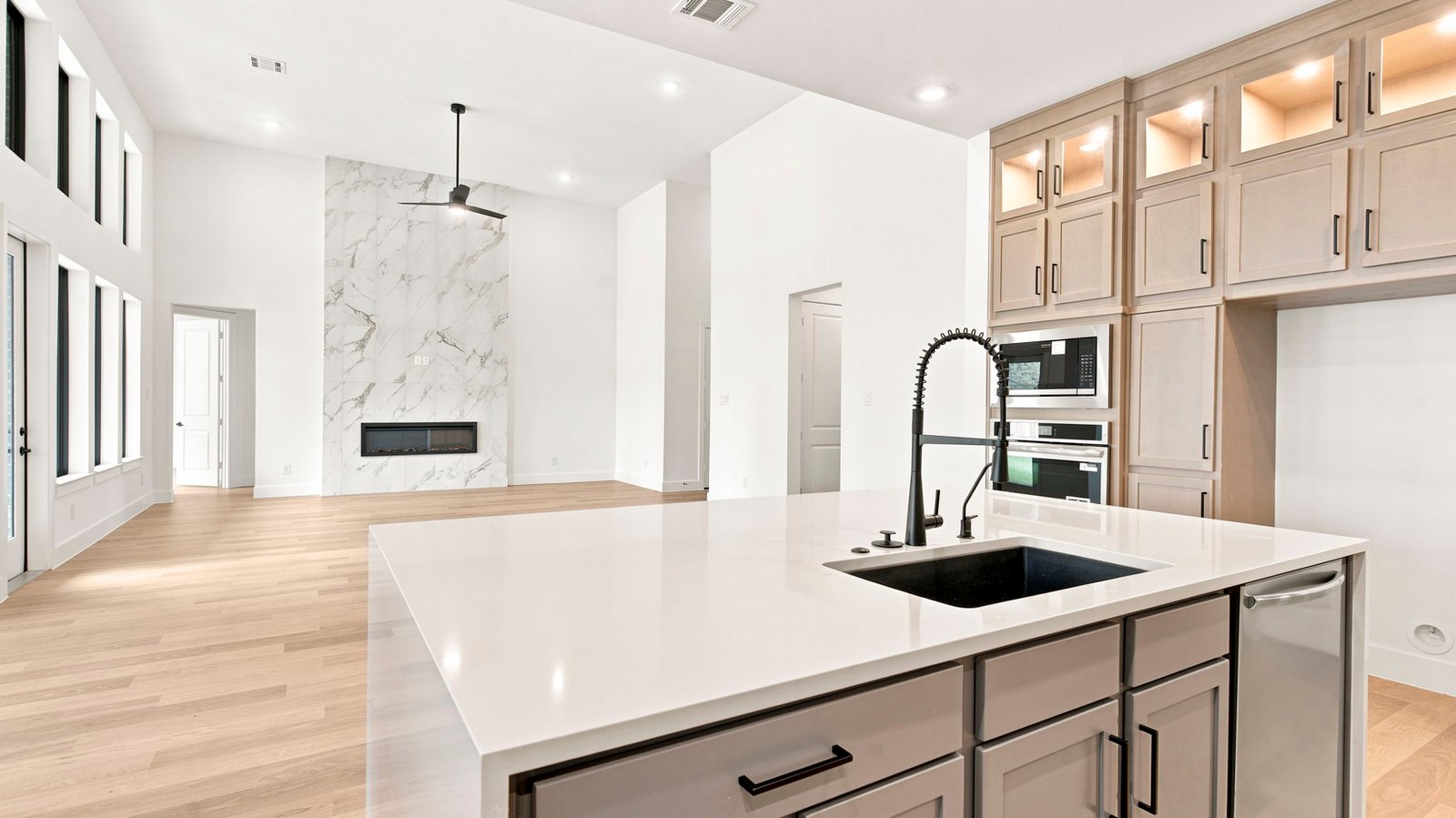 Luxurious and spacious kitchen with quartz countertops, stainless steel appliances, wood cabinets with natural stain, expansive storage and an island with bar seating.