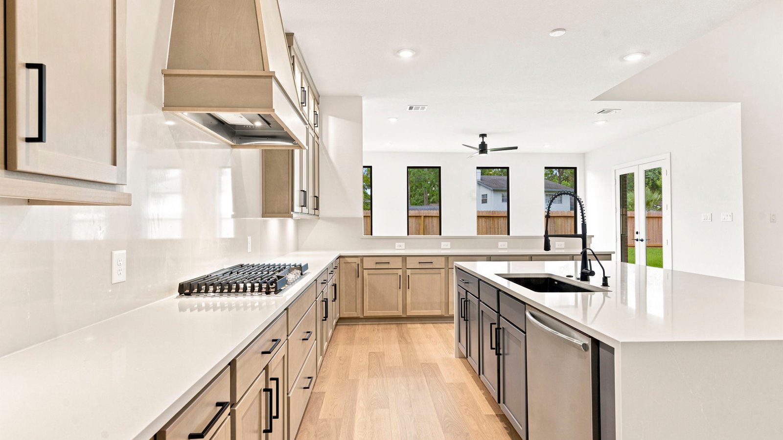 Luxurious and spacious kitchen with quartz countertops, stainless steel appliances, wood cabinets with natural stain, expansive storage and an island with bar seating.