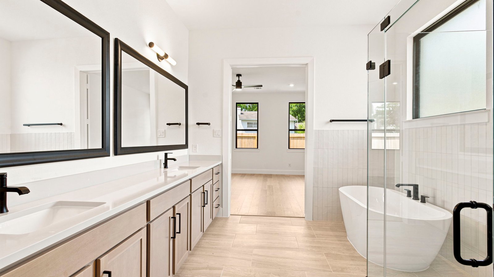 Luxurious primary bathroom with dual vanities, a soaking tub, and separate glass-enclosed walk in shower